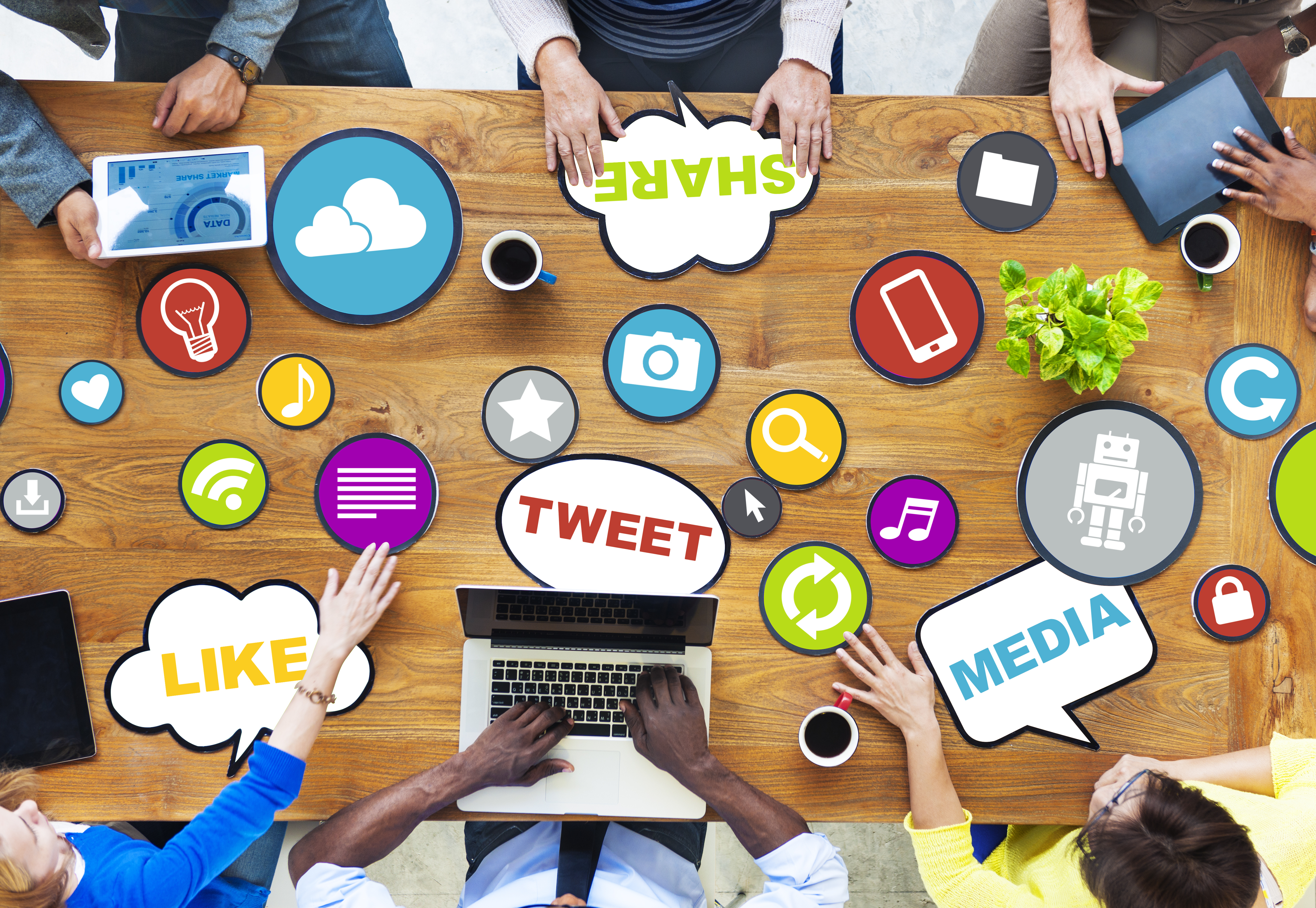 Social Media Marketers sitting across a board room table with icons representing social media topics